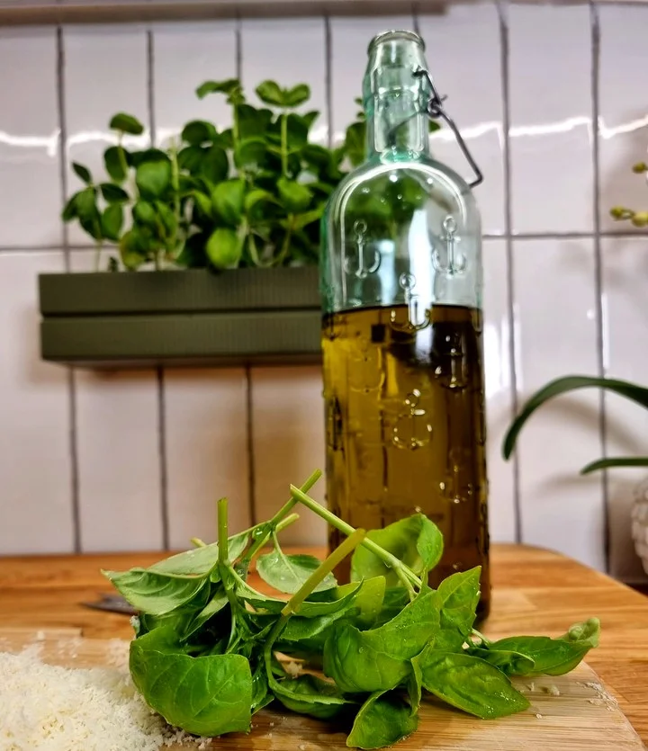 Fresh basil harvested from a Herbs2Hand Linea module on a chopping board with olive oil and parmesan